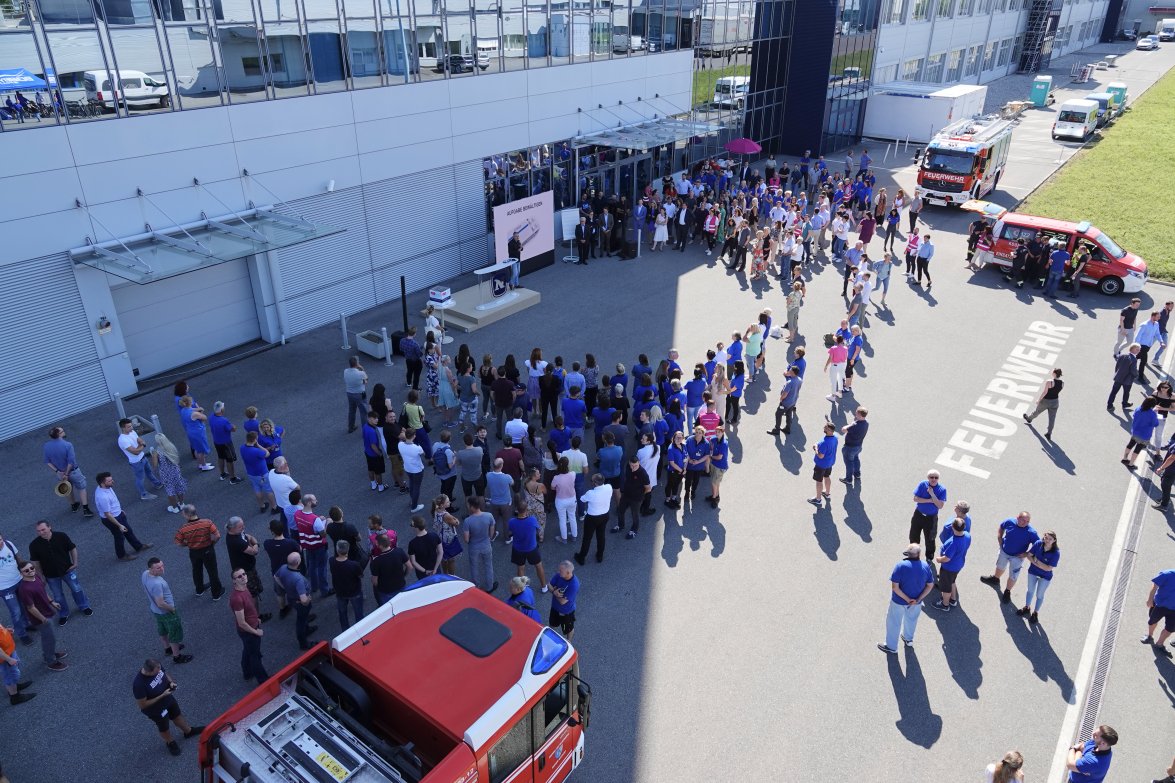NOVOMATIC employees in blue workingclothes in the yard of HQ in Gumpoldskirchen during a presentation with stage