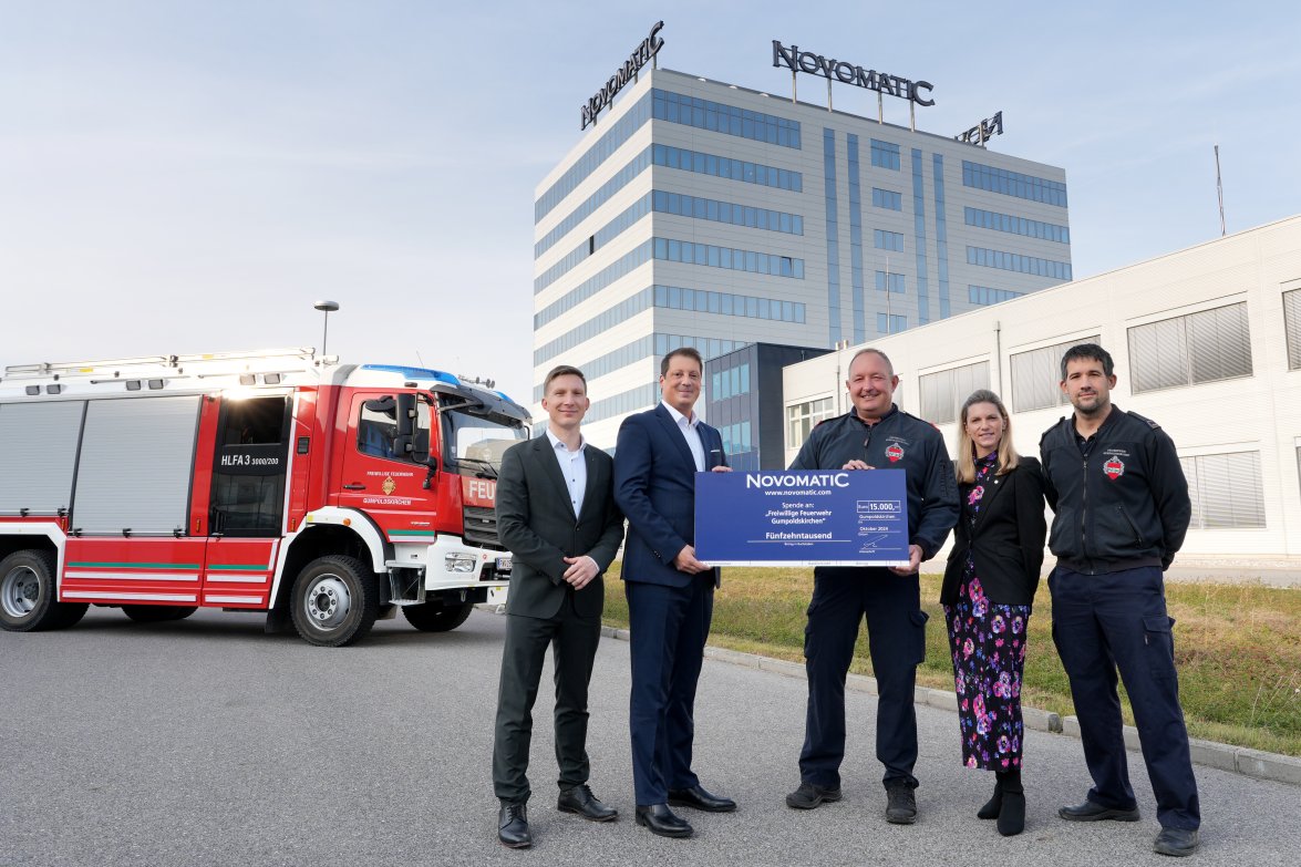 NOVOMATIC Geschäftsführung mit Feuerwehrvertretern vor einem Feuerwehrauto und HQ Gumpoldskirchen