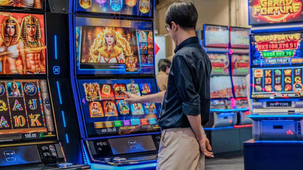 Nahaufnahme mehrere Cabinets von NOVOMATIC mit Interessentin auf der G2E Asia